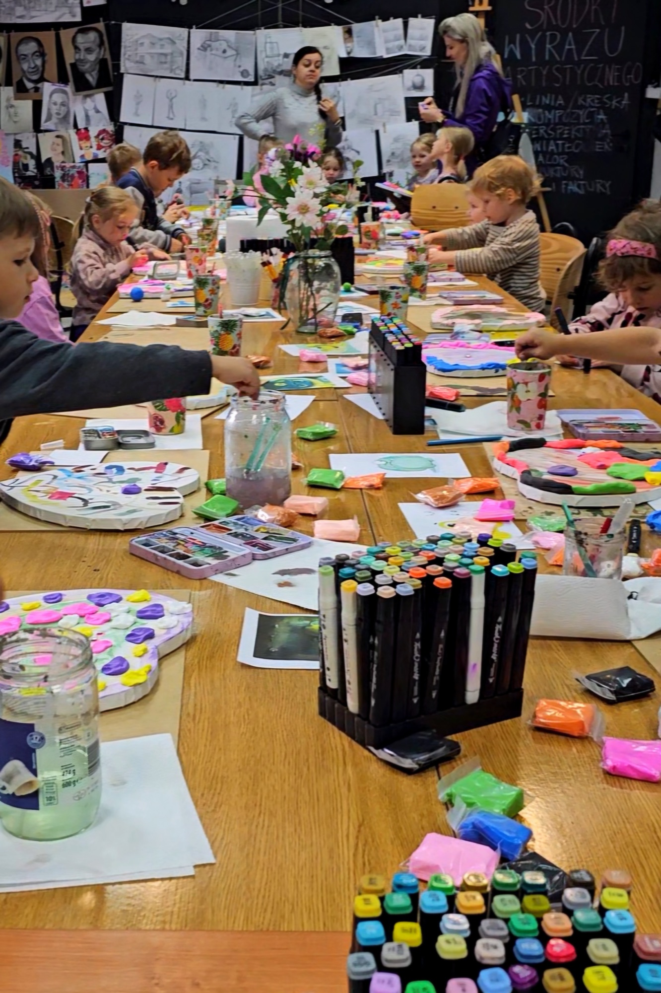 Warsztaty artystyczne dla grupy szkolnej w pracowni Academy of Art w Ełku, dzieci malują przy wspólnym stole